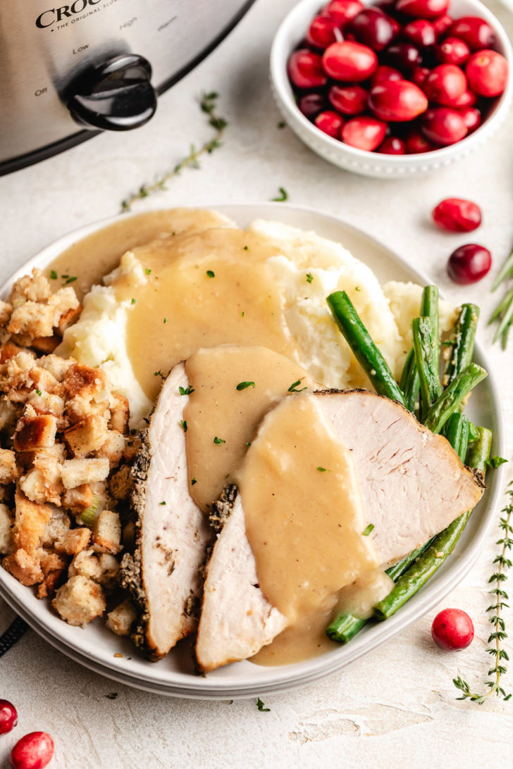 Slices of crockpot garlic herb turkey breast with gravy.