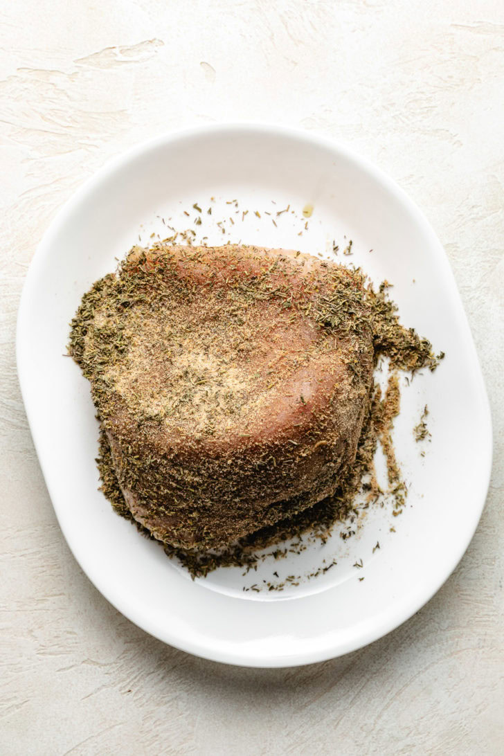 Uncooked turkey breast topped with herbs.