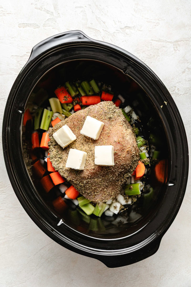 Turkey breast in a crockpot topped with butter.