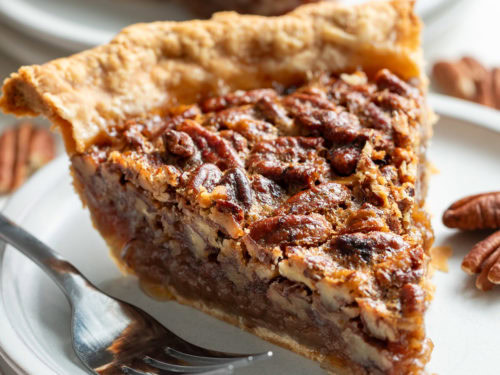 Fork next to a slice of pecan pie.