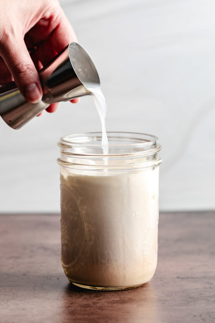 Vanilla vodka being poured into a mason jar.