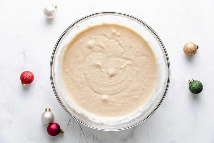 Easiest Eggnog Waffles Bowl of batter with holiday ornaments.