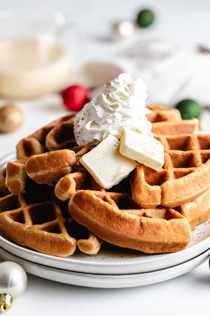 Stack of eggnog waffles with whipped cream.