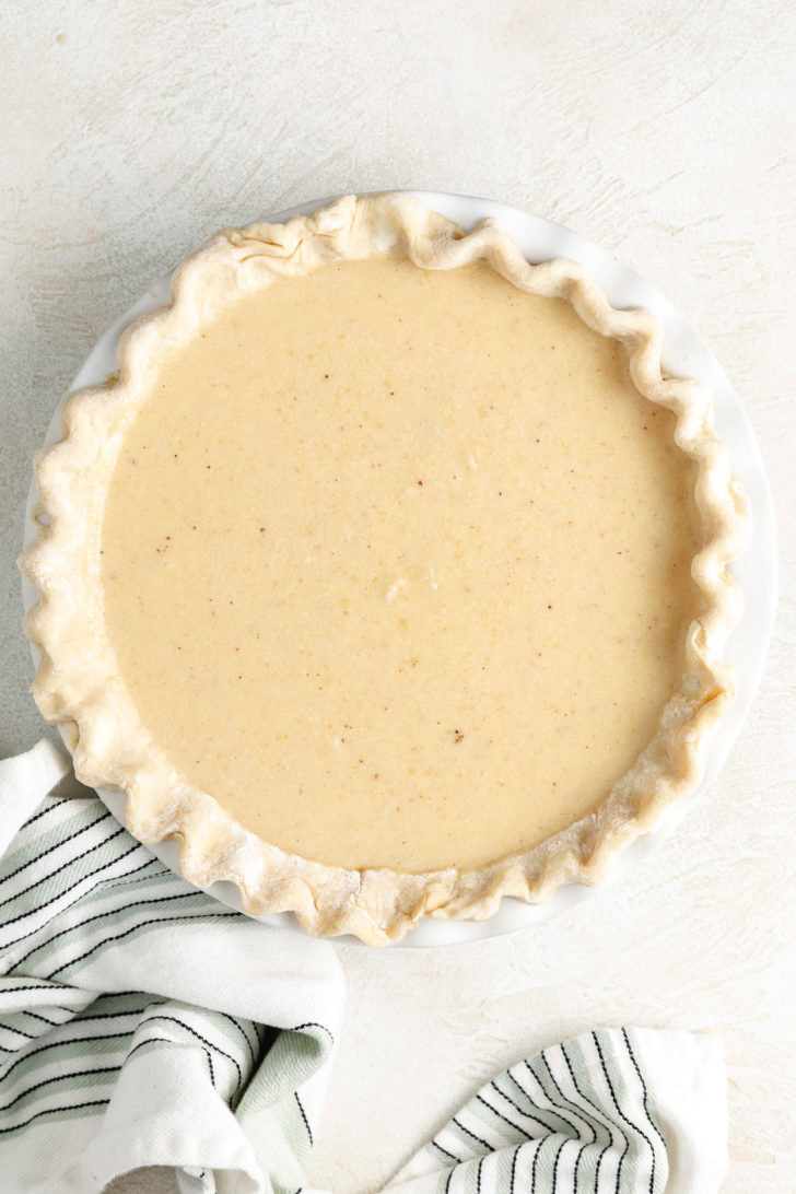 Unbaked buttermilk pie filling in a crimped pie crust.