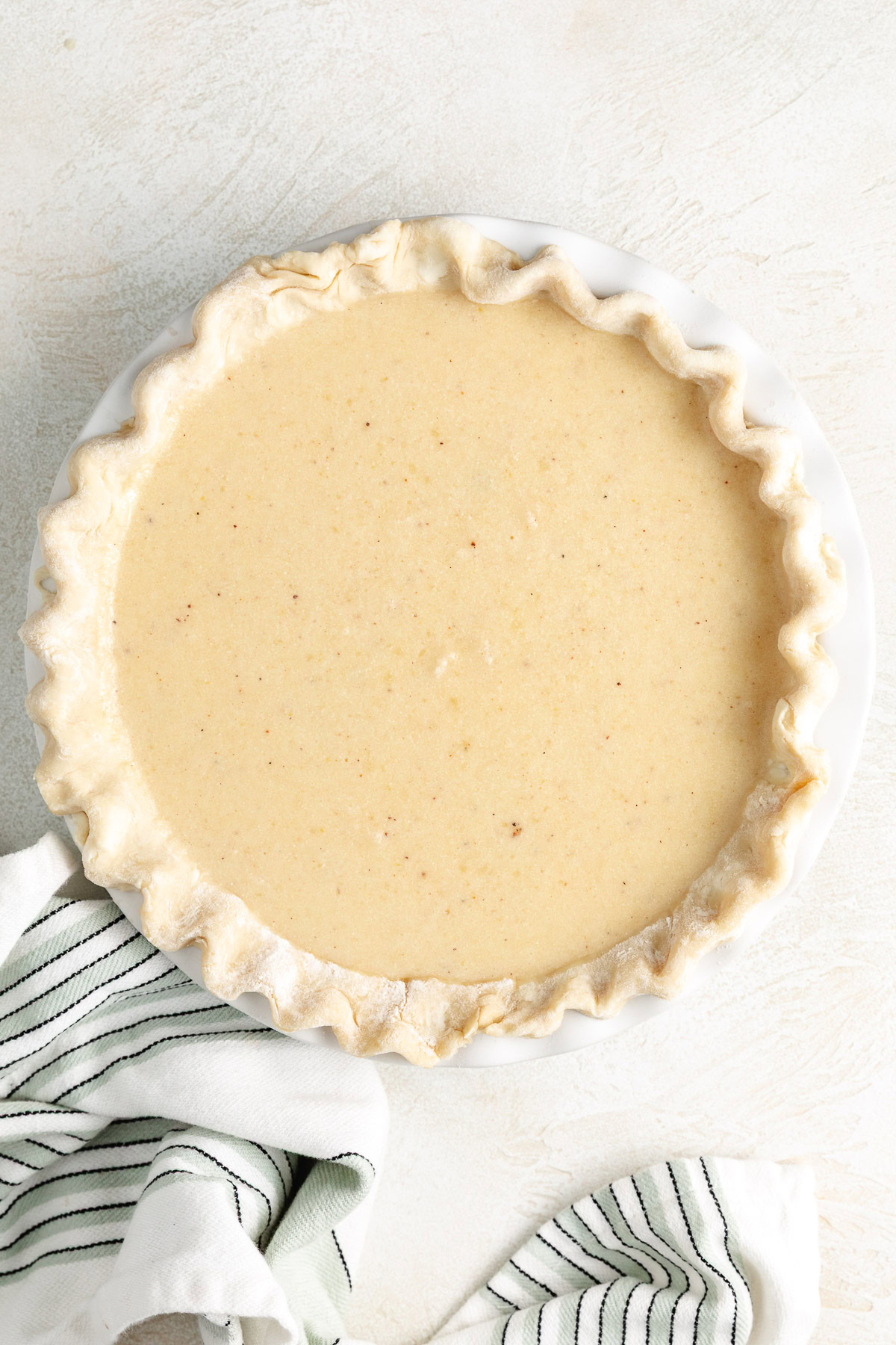 Unbaked buttermilk pie filling in a crimped pie crust.