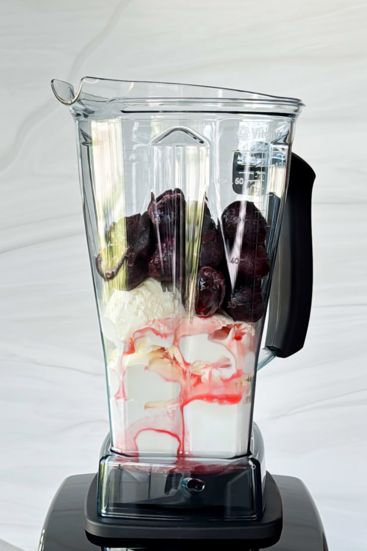 Blender filled with cherries and ice cream.