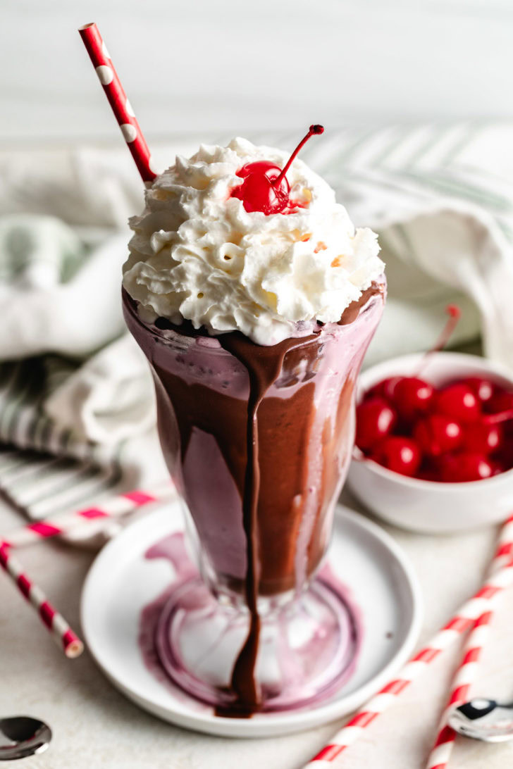 Cherry milkshake with whipped cream and a cherry.