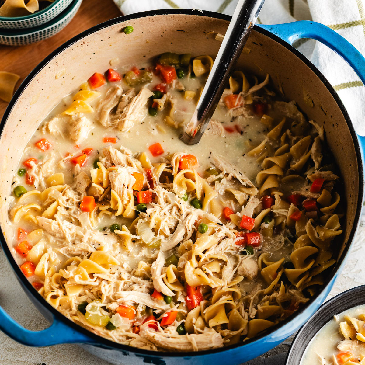 Creamy chicken noodle soup in a blue Dutch oven.