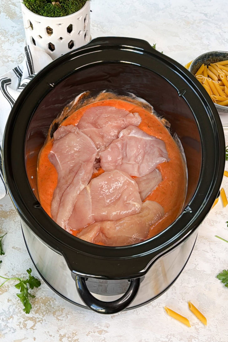 Chicken breasts in marinara and alfredo sauce in a crockpot.