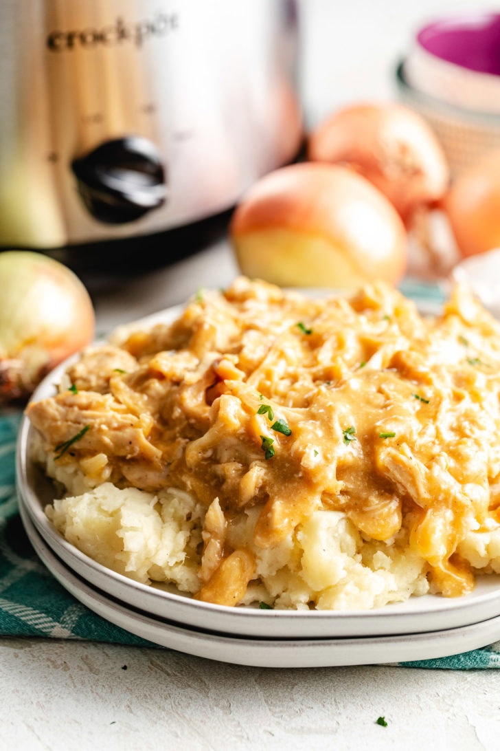 Crockpot chicken and gravy spooned over mashed potatoes.