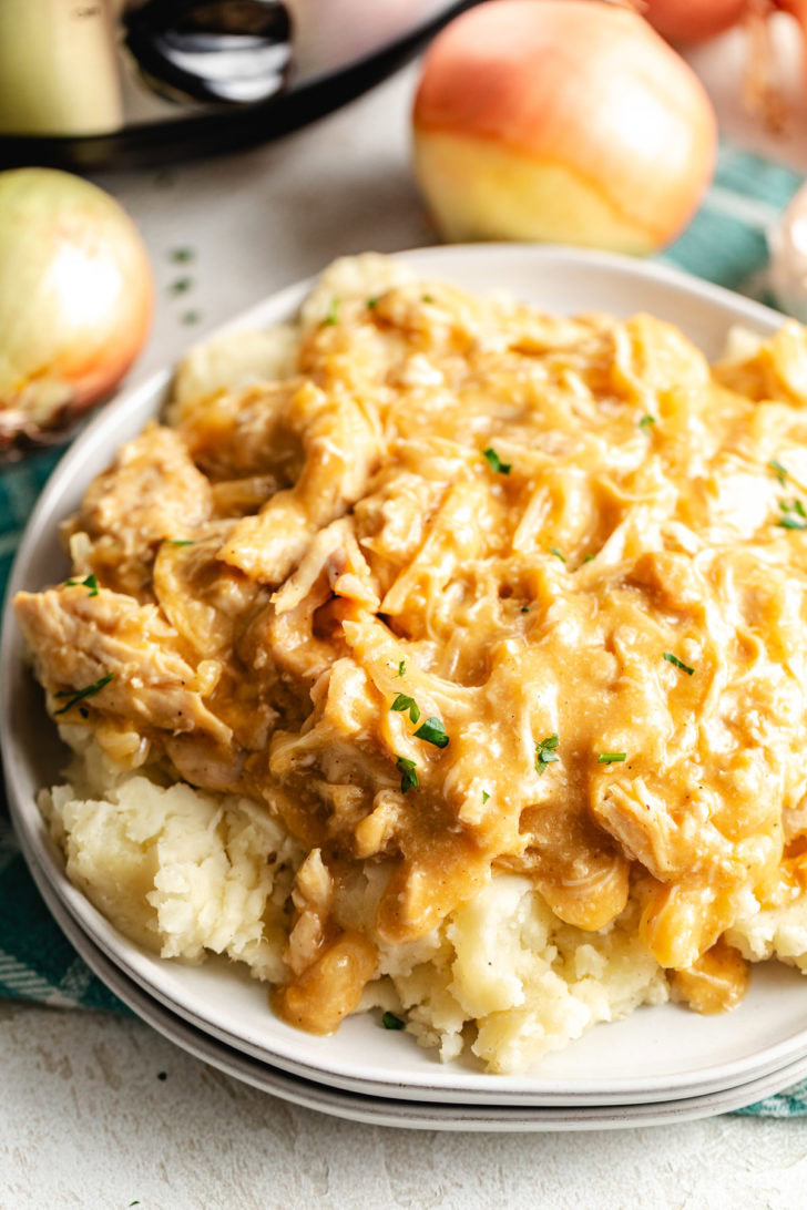 Close-up of crockpot chicken and gravy served on mashed potatoes.