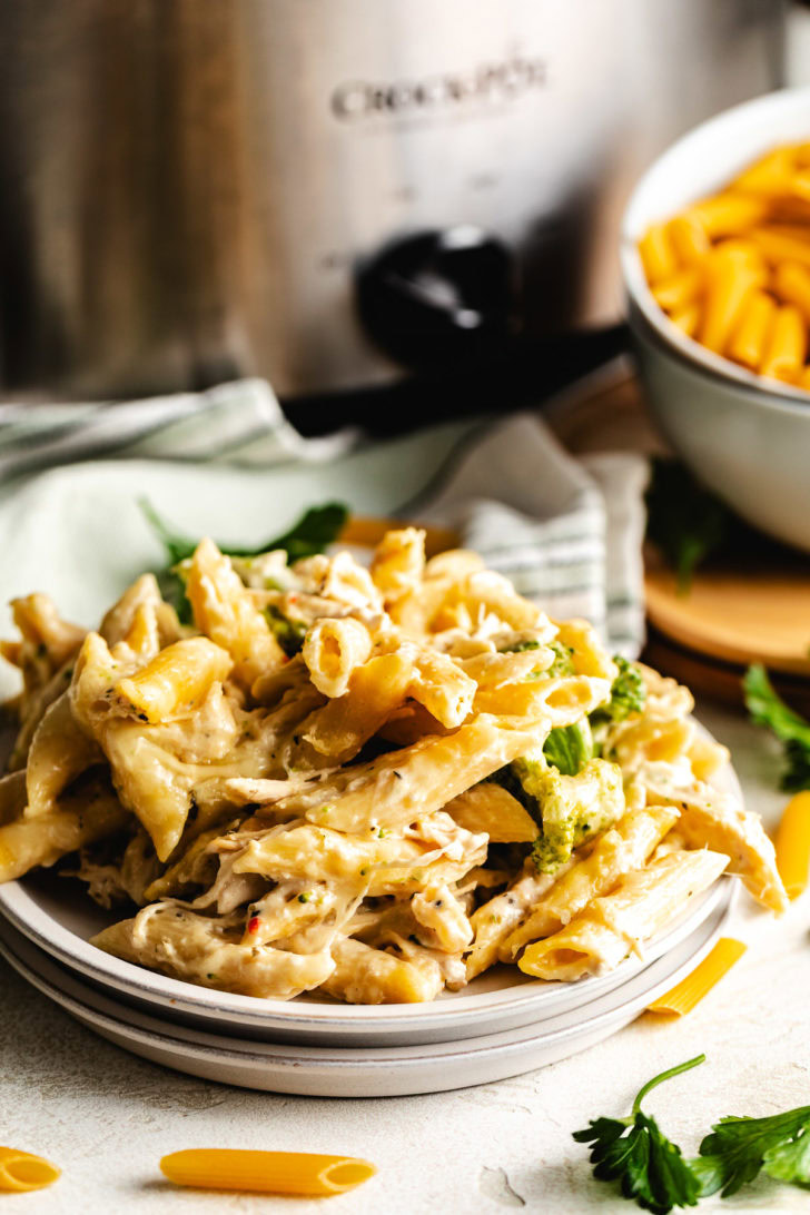 Crockpot Italian chicken pasta piled on a plate with penne, shredded chicken, and broccoli in a creamy sauce.
