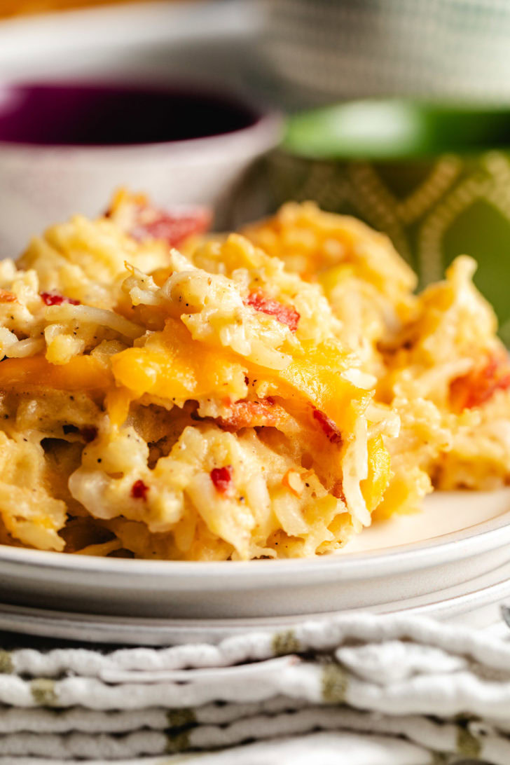 Close-up of hashbrown casserole showing creamy potatoes, cheddar pockets, and bacon pieces.