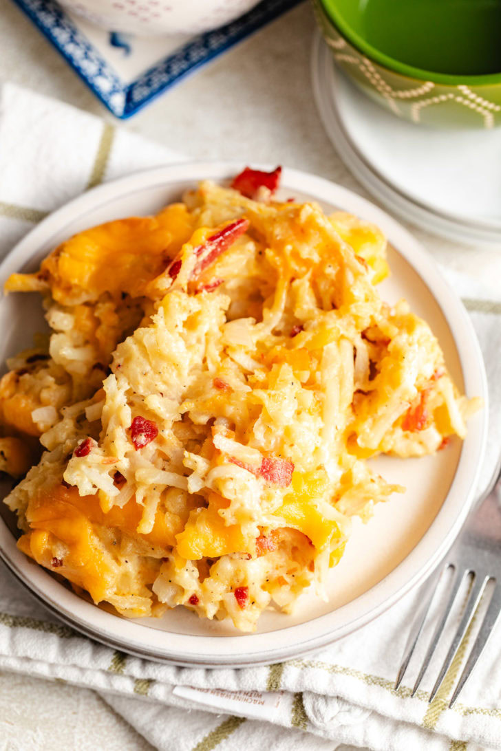 Overhead view of cheesy shredded potato bake on a plate with a striped kitchen towel.