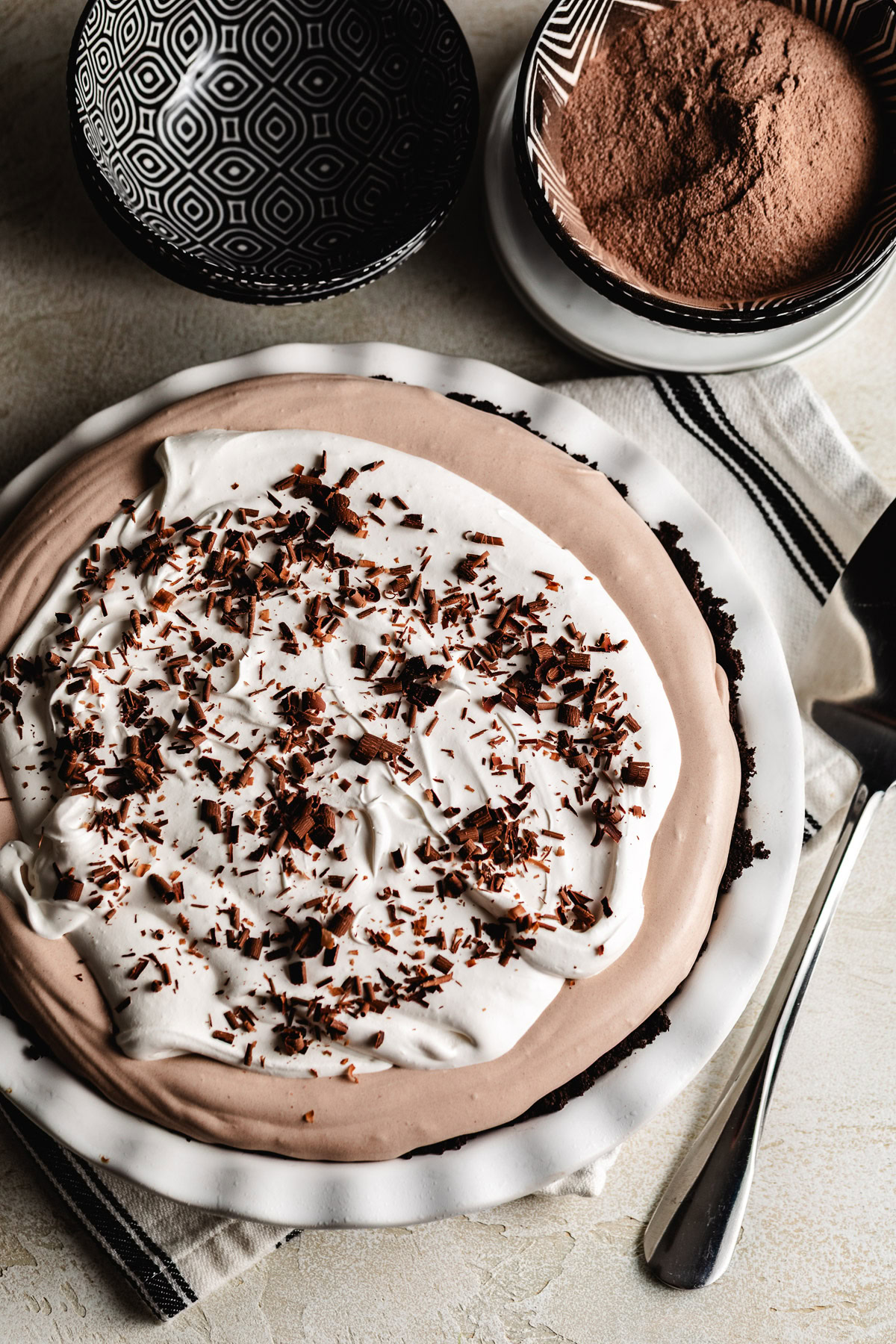 Finished hot chocolate pie in a white dish with a whipped topping center and chocolate shavings on top.