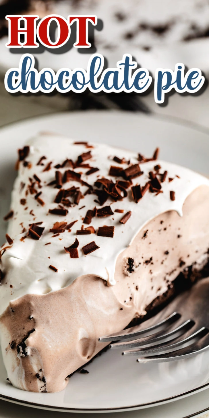 Slice of hot chocolate pie on a white plate with a fork, topped with whipped topping and chocolate curls.