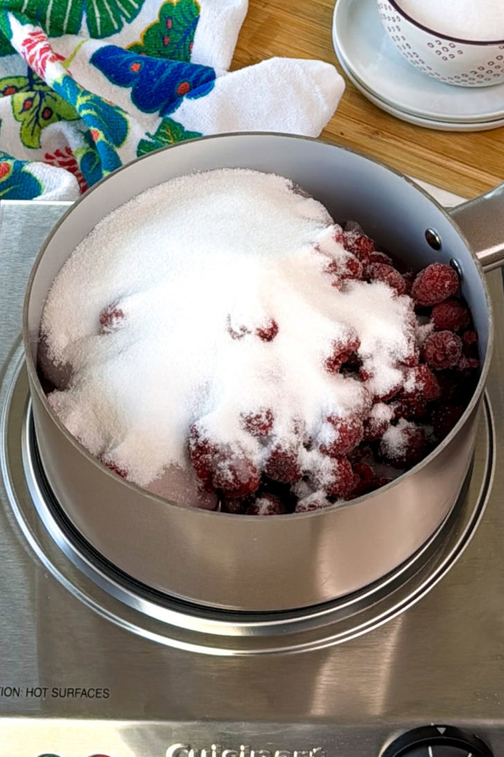 Raspberries and sugar in a pot.