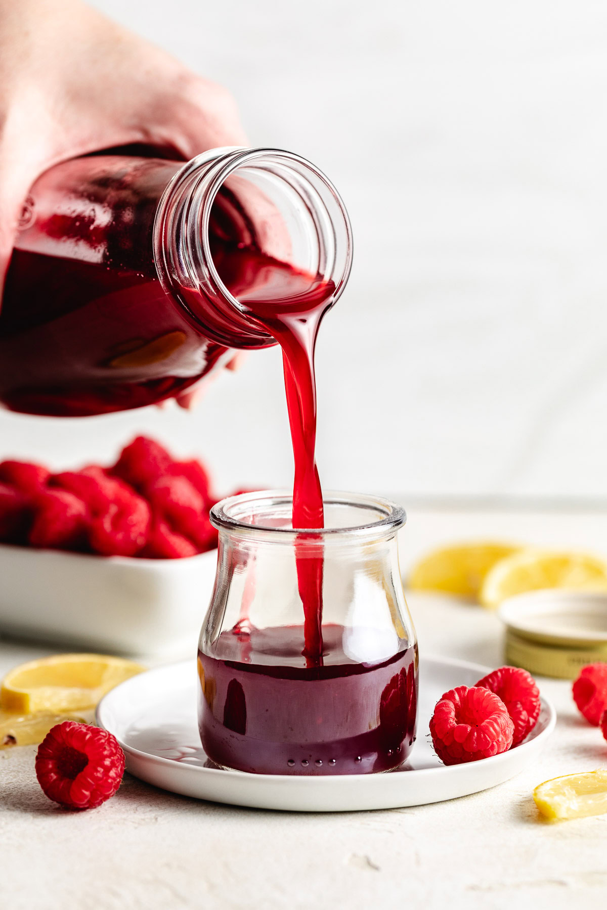 Pouring raspberry simple syrup into glass.