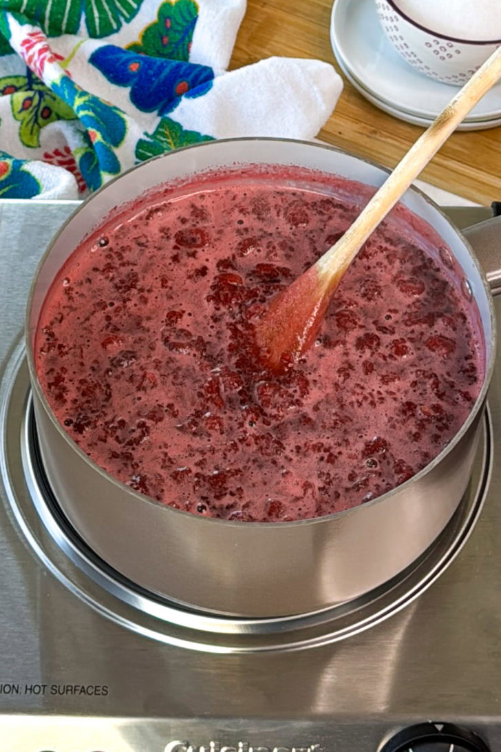 Cooking raspberry syrup in saucepan.