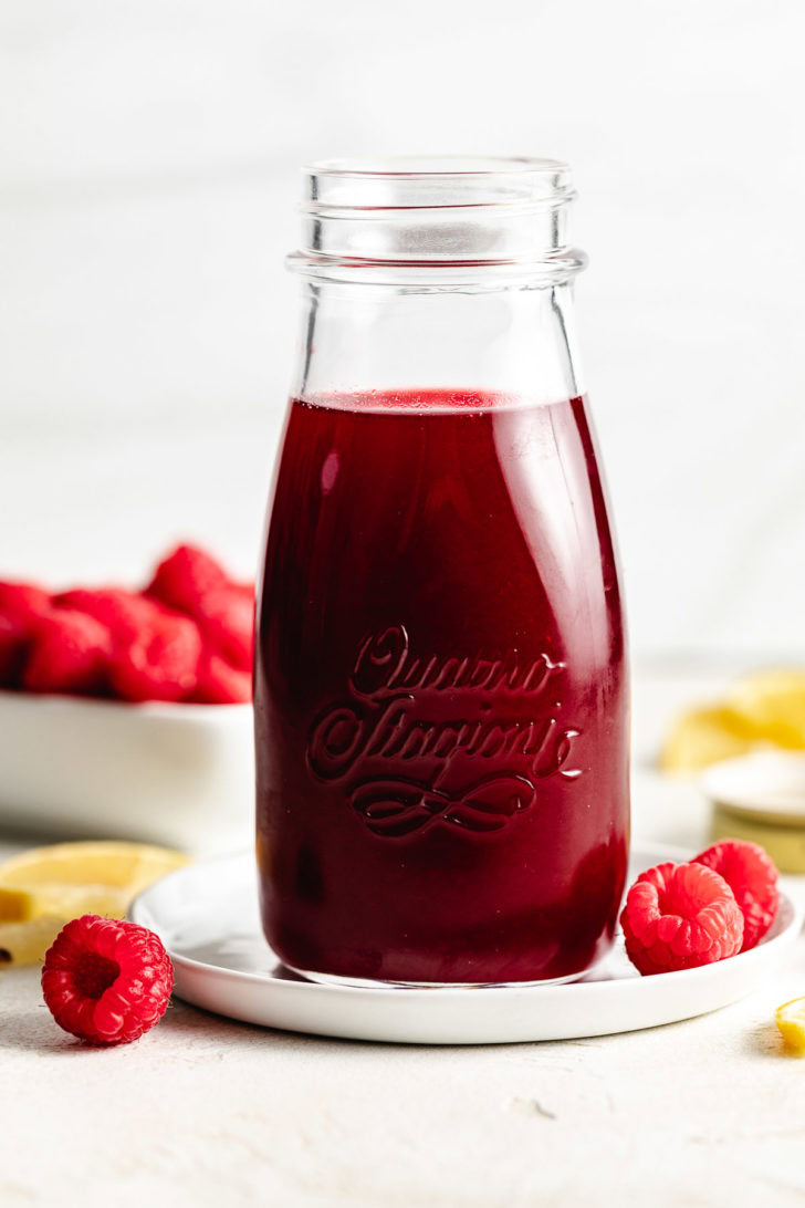 Bottle of raspberry syrup with fruit.
