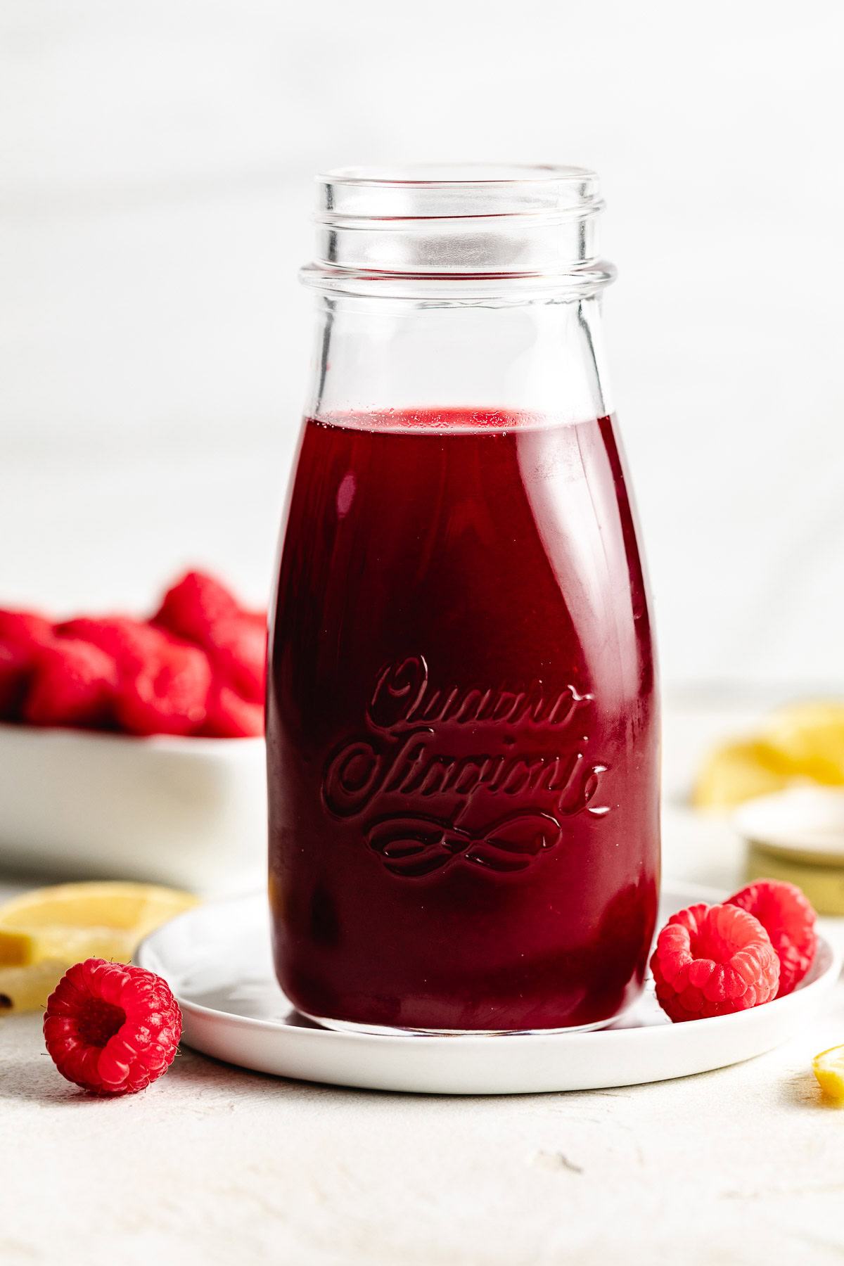 Bottle of raspberry syrup with fruit.