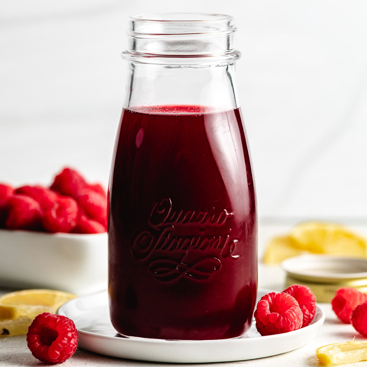 Jar of raspberry simple syrup with fruit.