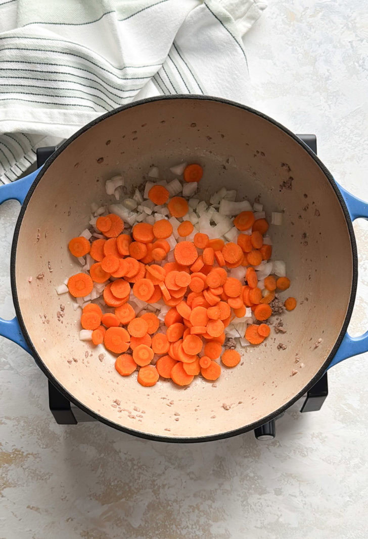 Sliced carrots and chopped onions sautéing together.