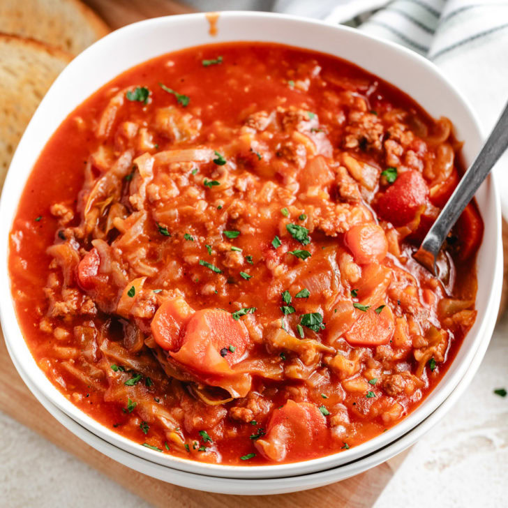 A bowl of cabbage roll soup filled with ground beef, cabbage, and carrots in tomato broth.