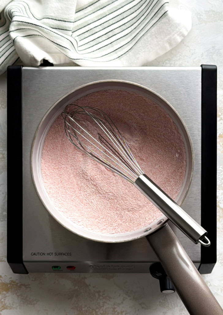 Whisk resting in a saucepan of dry strawberry gelatin, sugar, and cornstarch.