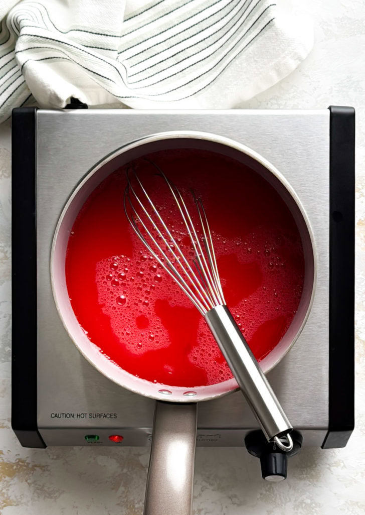 Strawberry pie filling mixture simmering in a saucepan.