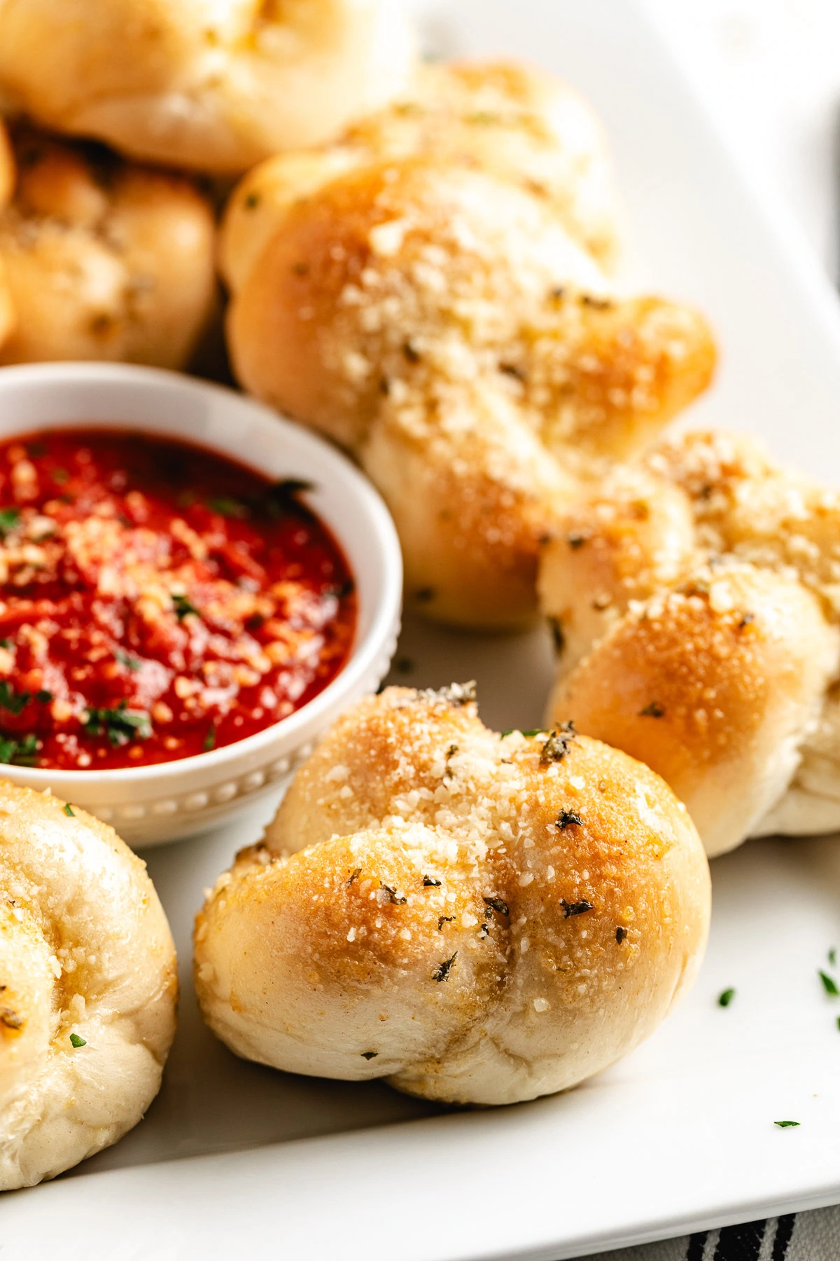Garlic knots piled beside marinara for serving.