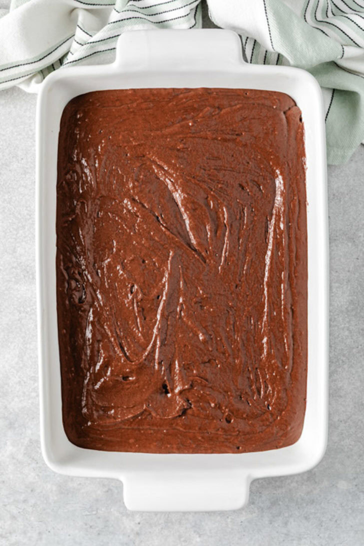 White baking dish filled with chocolate cake with Guinness batter spread into an even layer.