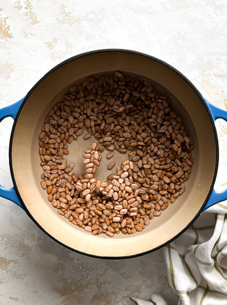 Dutch oven filled with dried pinto beans for ham and beans recipe.