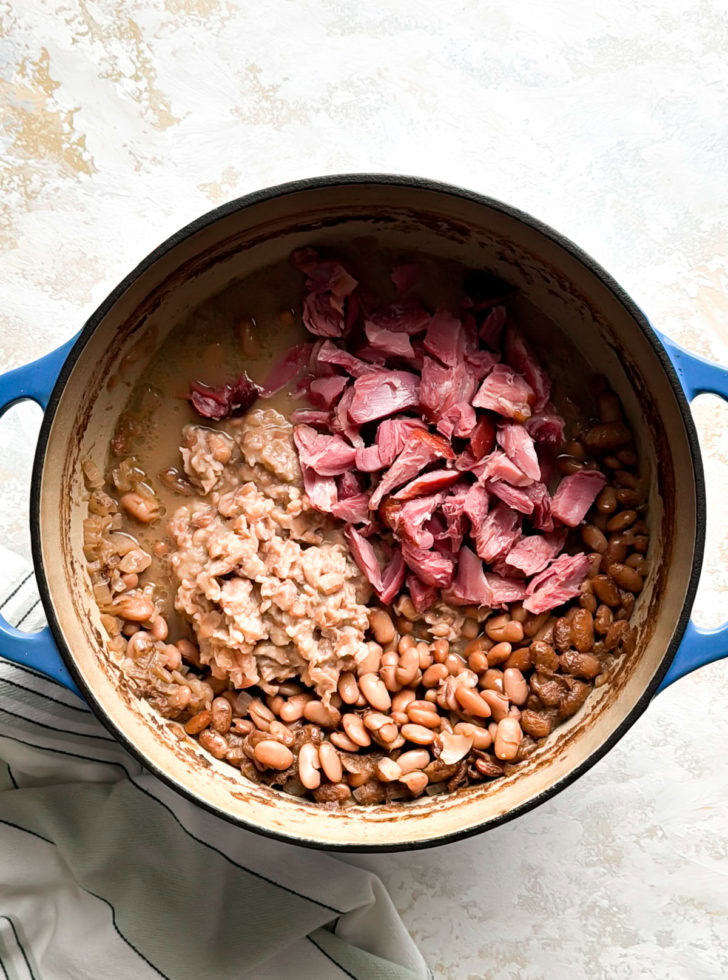 Shredded ham and mashed pinto beans in a Dutch oven, ready to mix.