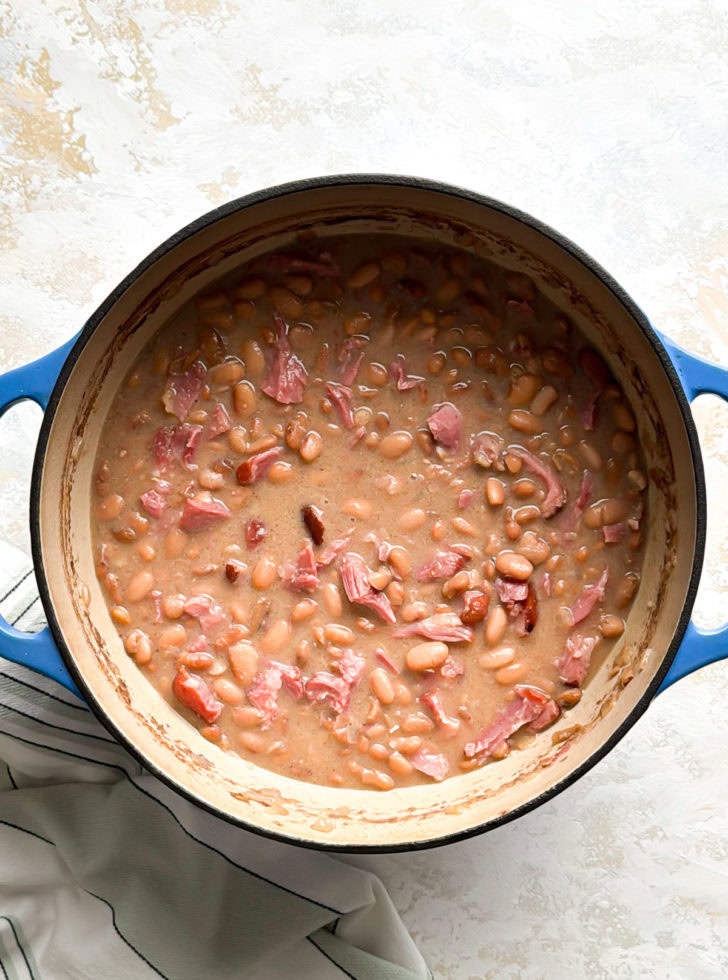 Pot of creamy pinto beans and ham in a thick broth.