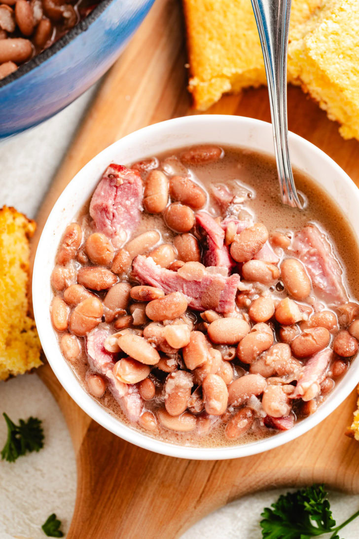 Top view of pinto beans and ham served with cornbread pieces.