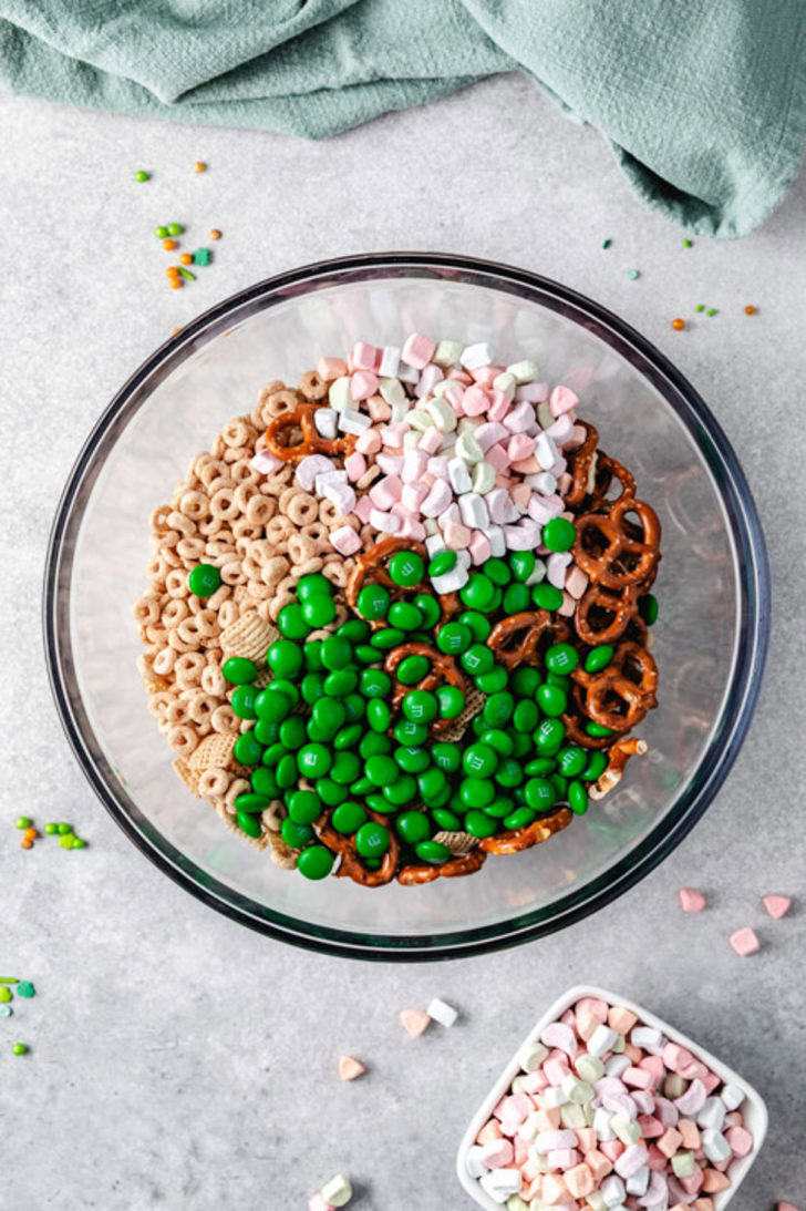 Large mixing bowl with cereal, pretzels, green chocolate candies, and marshmallows.