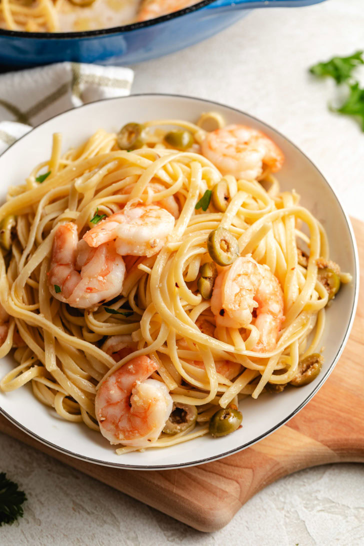 Shrimp and linguine piled in a white bowl.