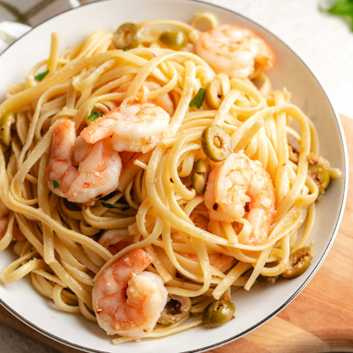 Bowl of mediterranean shrimp pasta with green olives.
