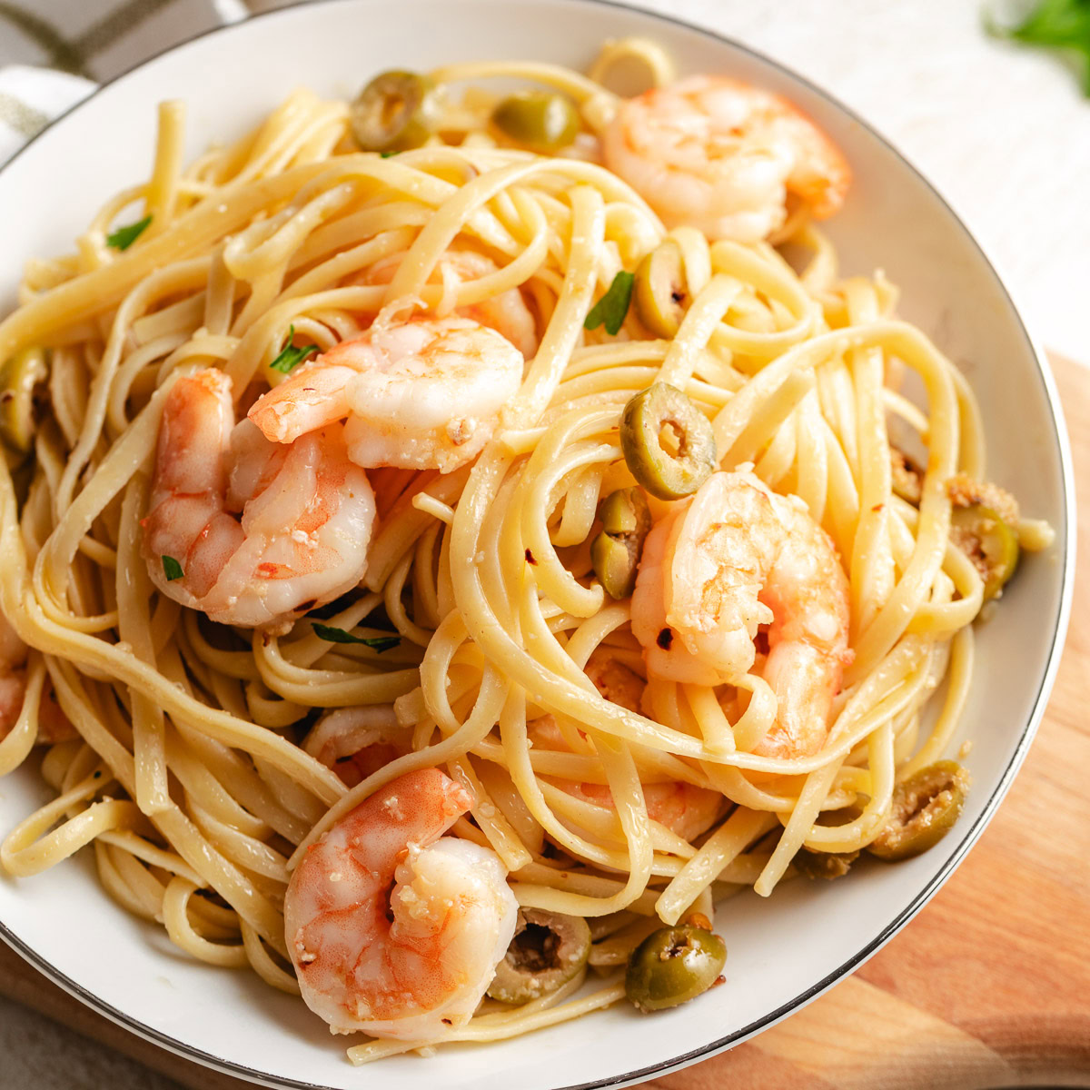 Bowl of mediterranean shrimp pasta with green olives.