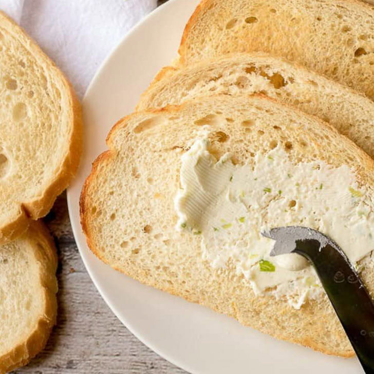 Close up view of sour cream butter being spread over toast.