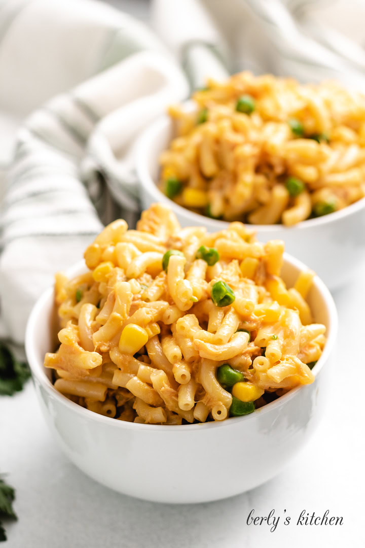 Tuna mac and cheese in two white bowls on a wood surface.