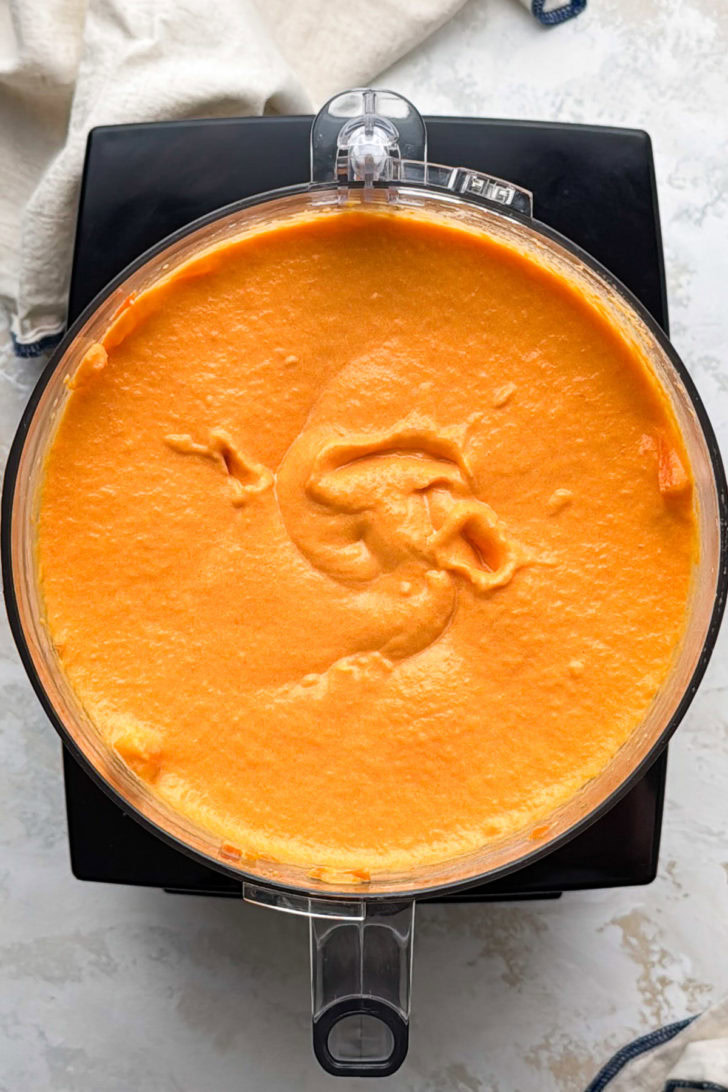Blended carrot soufflé mixture fills a food processor.