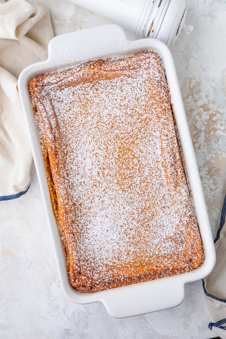 Baked carrot soufflé is dusted with powdered sugar in a baking dish.