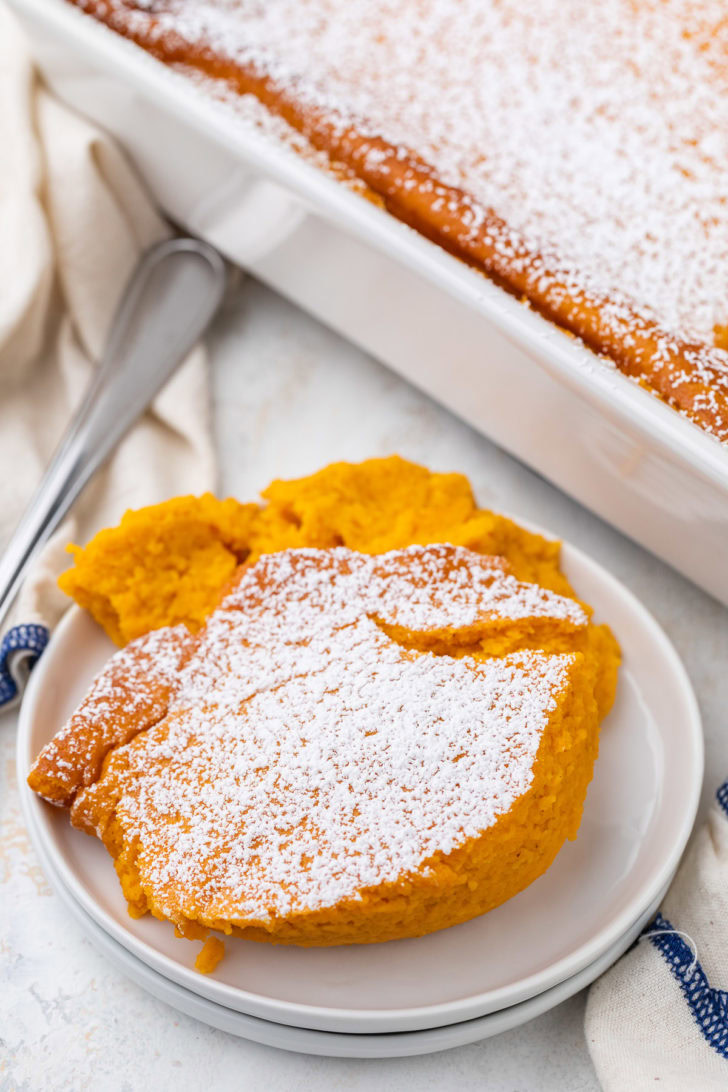 A plated slice of carrot casserole is dusted with powdered sugar.