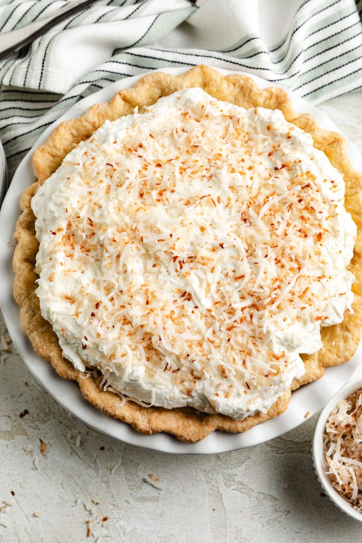 Coconut cream pie with whipped topping is shown from above.
