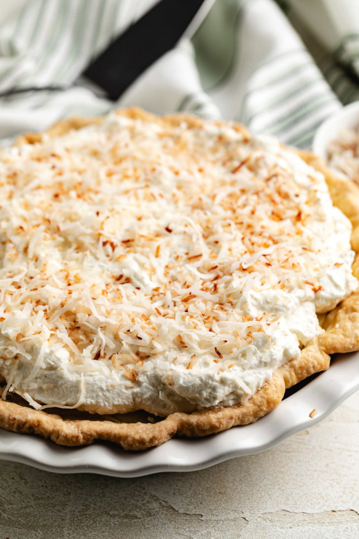 Coconut cream pie is garnished with toasted coconut on top.