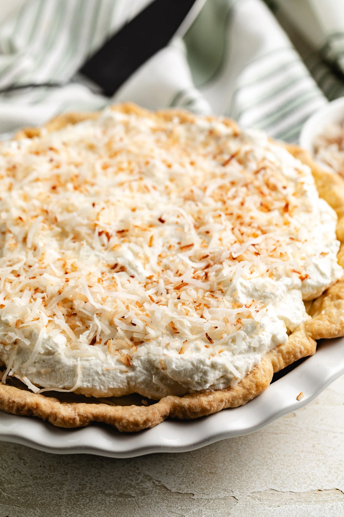 Coconut cream pie is garnished with toasted coconut on top.