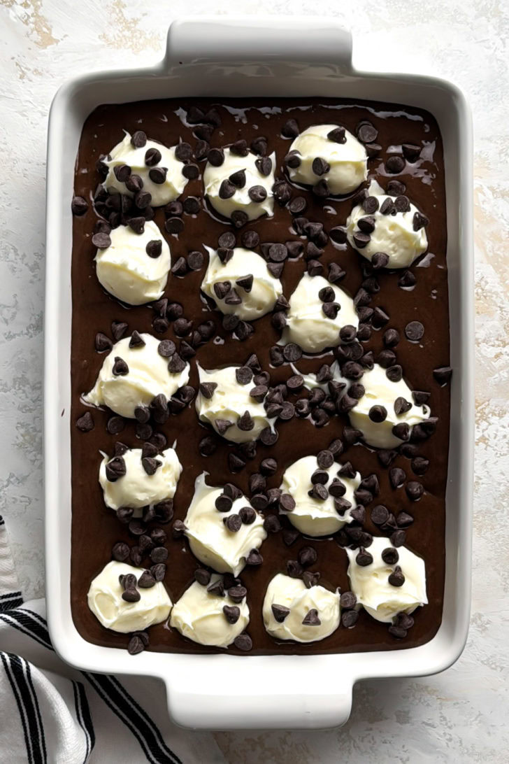 Cake batter, cream cheese filling, and chocolate chips in a baking dish.