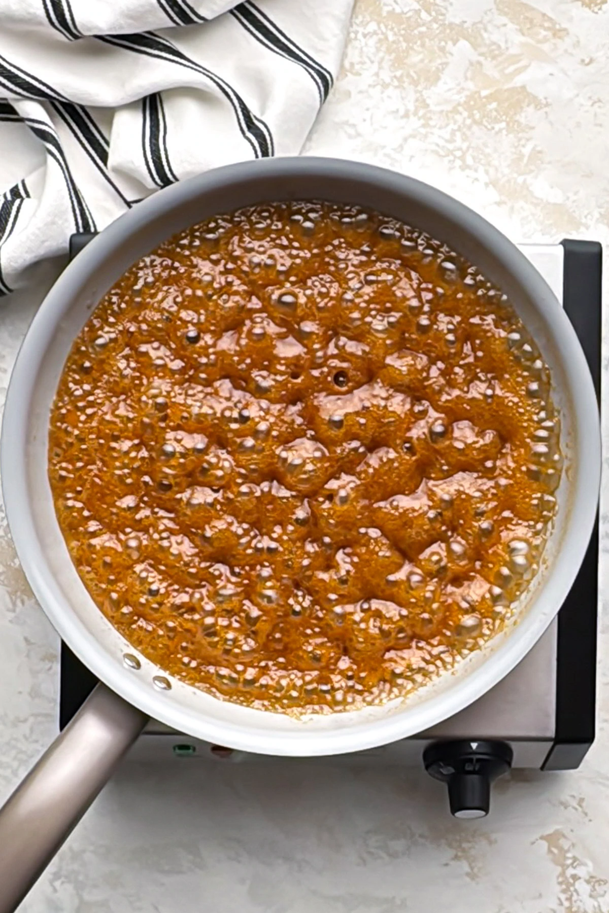 Glaze for ham bubbling in a saucepan as it thickens.
